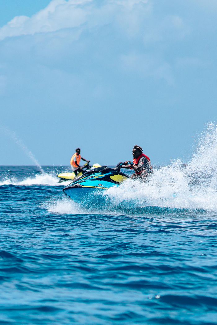 Two adults enjoy an exhilarating jet ski ride, capturing the thrill of sea adventure and speed.